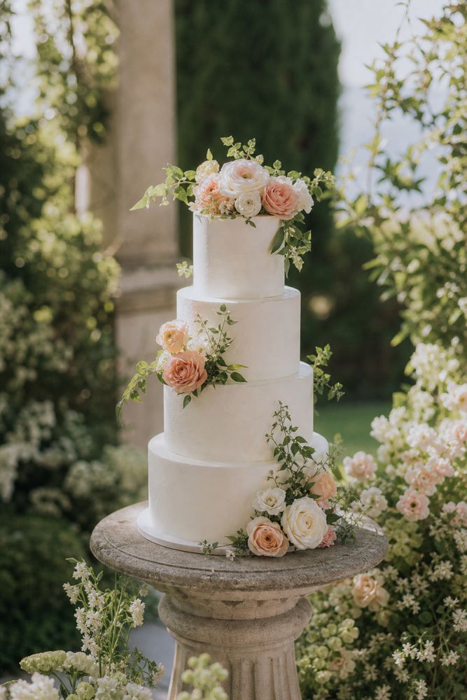 White buttercream wedding cake with fresh flowers on a stone pedestal
